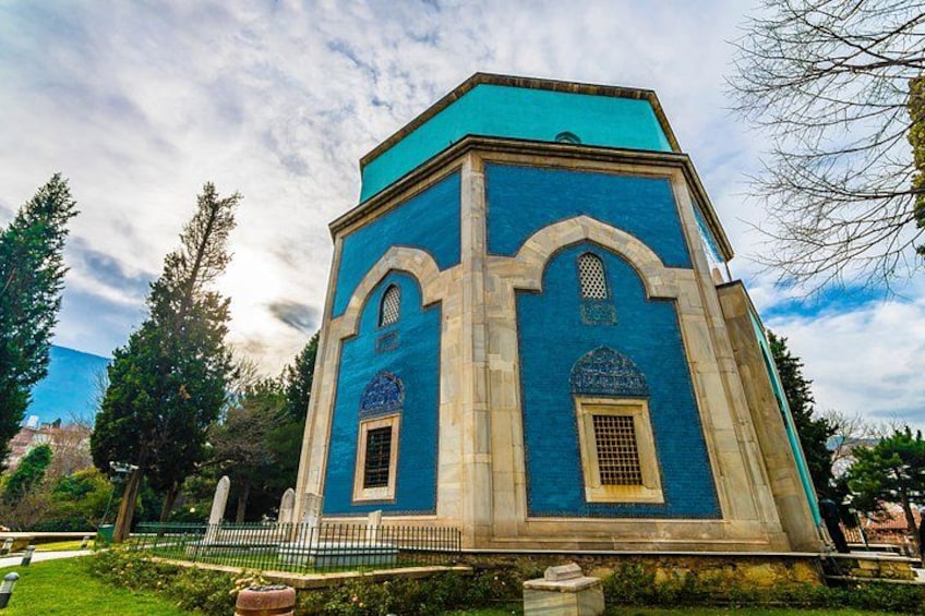 Un bâtiment bleu avec des fenêtres en arc de cercle et un toit recouvert de tuiles, entouré d’arbres et d’une clôture. 5