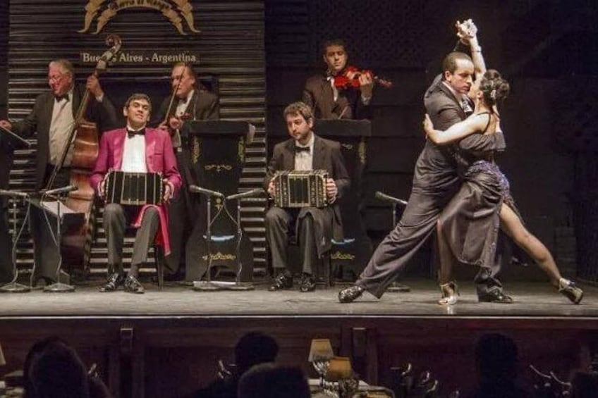 A tango performance with musicians and dancers on stage. 1