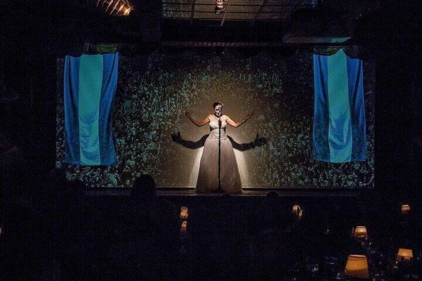 A stage with a person in a dress, curtains, and a backdrop. 4
