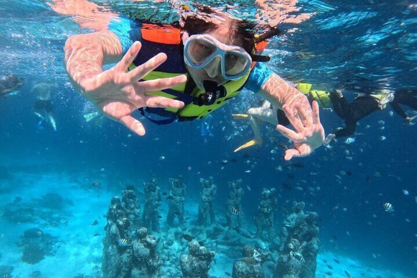 A person scuba diving underwater with a reef structure in the background. 3