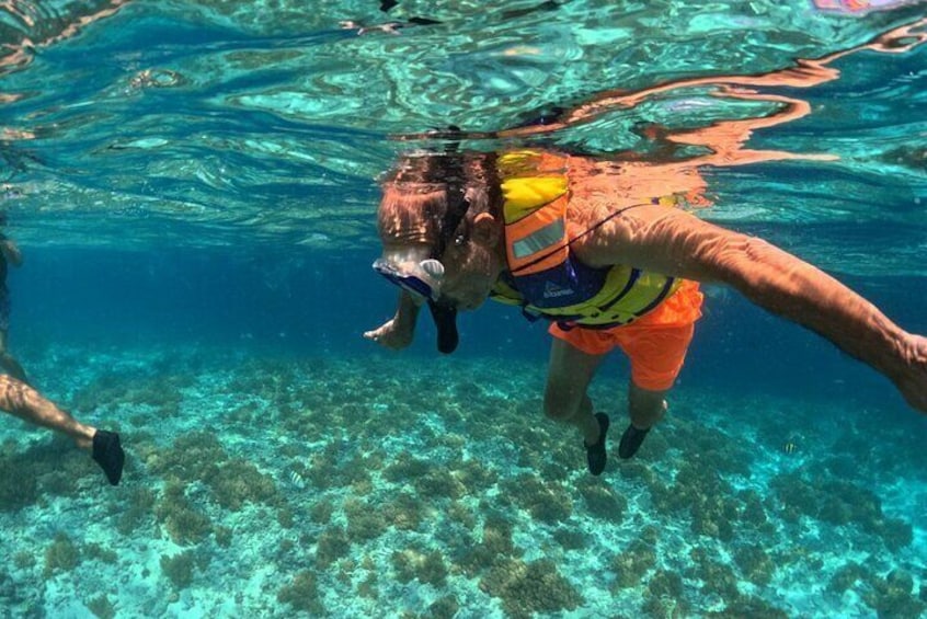 A person swimming underwater wearing a life jacket and goggles. 4