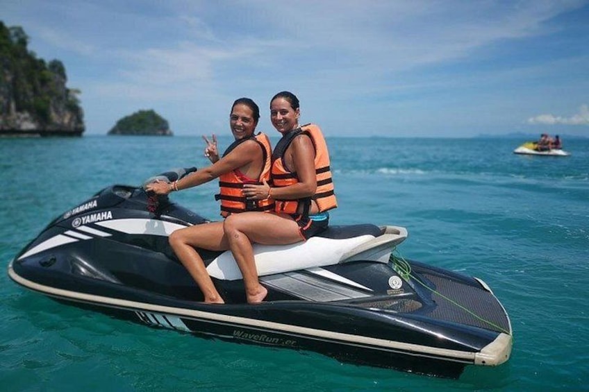 To personer på en Yamaha jetski i turkis vand under en klar himmel. 1