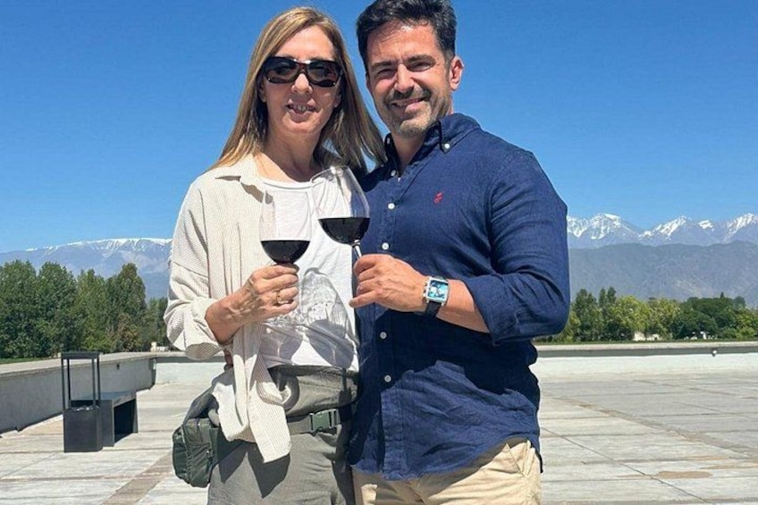 Two people holding wine glasses, with a mountainous landscape in the background. 5