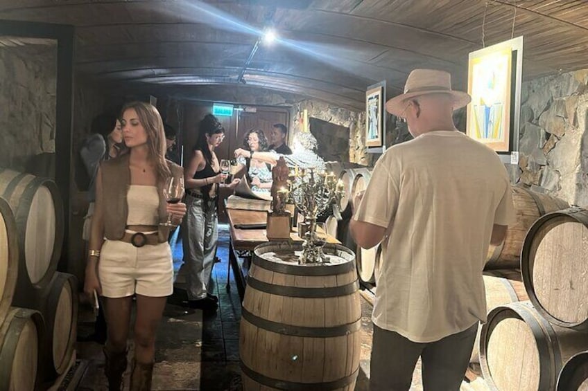 Une cave à vin avec des barriques en bois et une personne tenant un verre de vin. 4