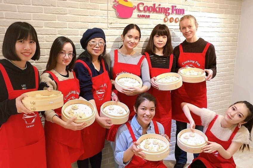 Un gruppo di persone con grembiuli rossi che tengono contenitori di legno pieni di cibo. 1