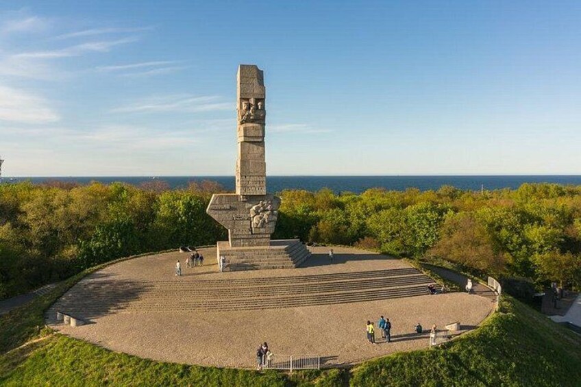 Un alto monumento a base circolare, circondato da un'area verdeggiante con alberi e un cielo sereno. 2