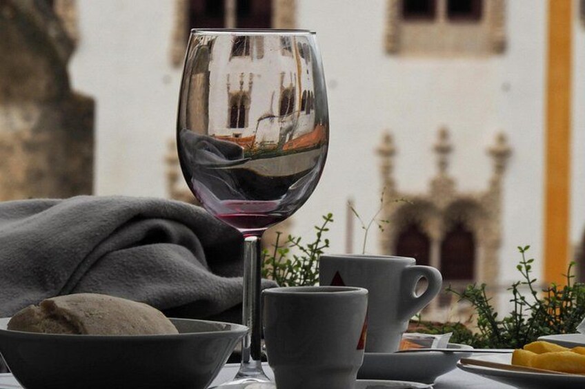 A table with a wine glass, bowls, and a cup, set against a building with arches. 2