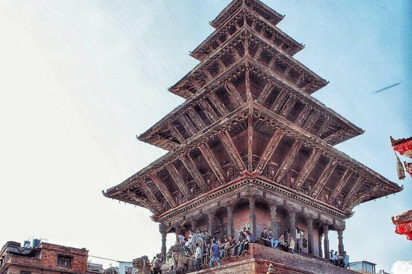 A multi-tiered pagoda with intricate wooden architecture and a group of people gathered at its base. 4