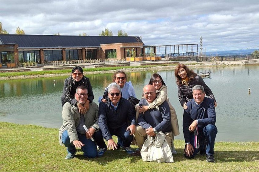 A group of people posing by a lake with modern buildings in the background. 2