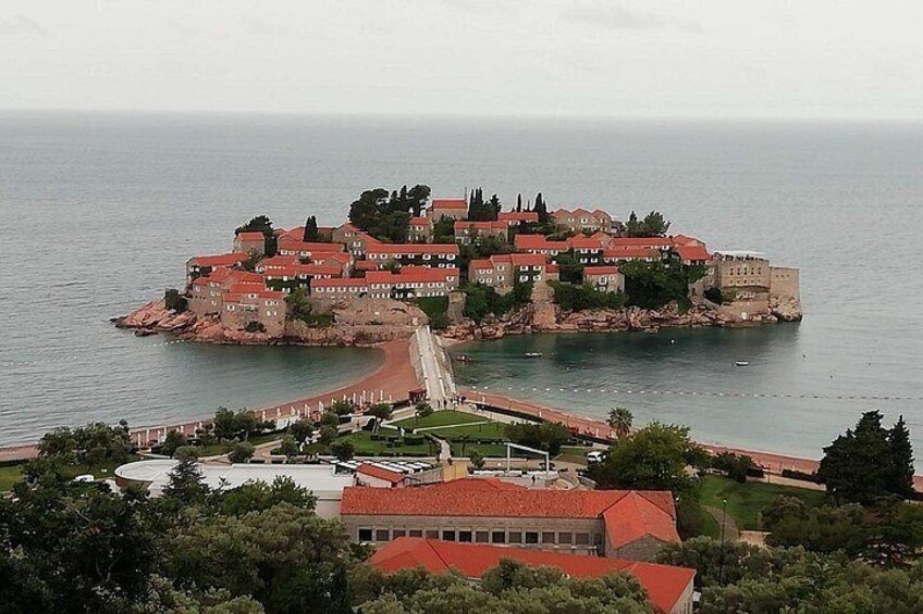 A coastal fortress with red-roofed buildings, a central walkway, and a view of the sea. 5