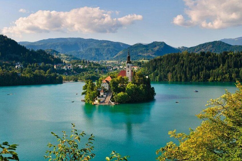 Un lago rodeado de montañas, una iglesia en una pequeña isla y un cielo despejado. 1