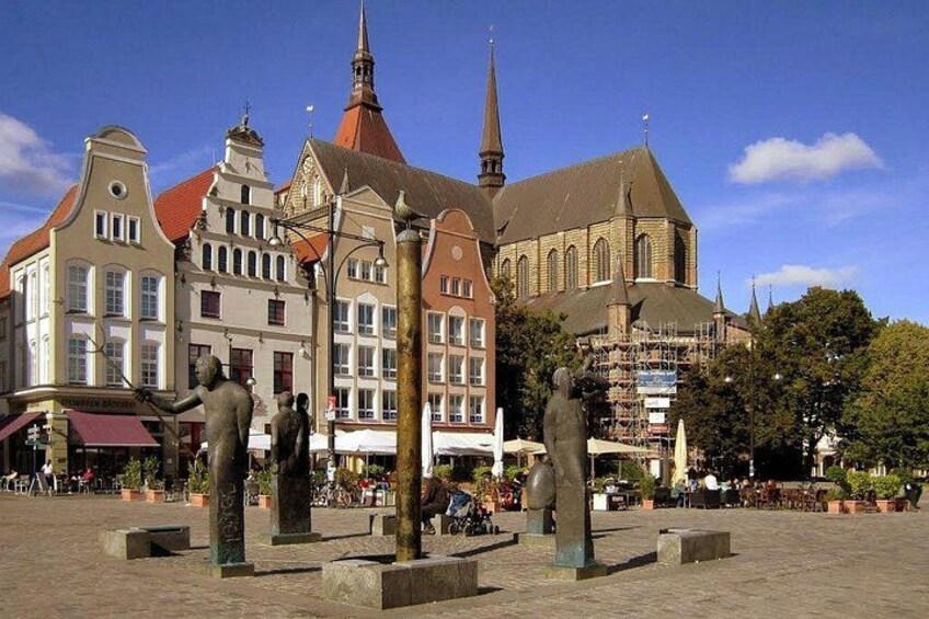 Une place historique bordée d’immeubles, d’une église et de statues. 1
