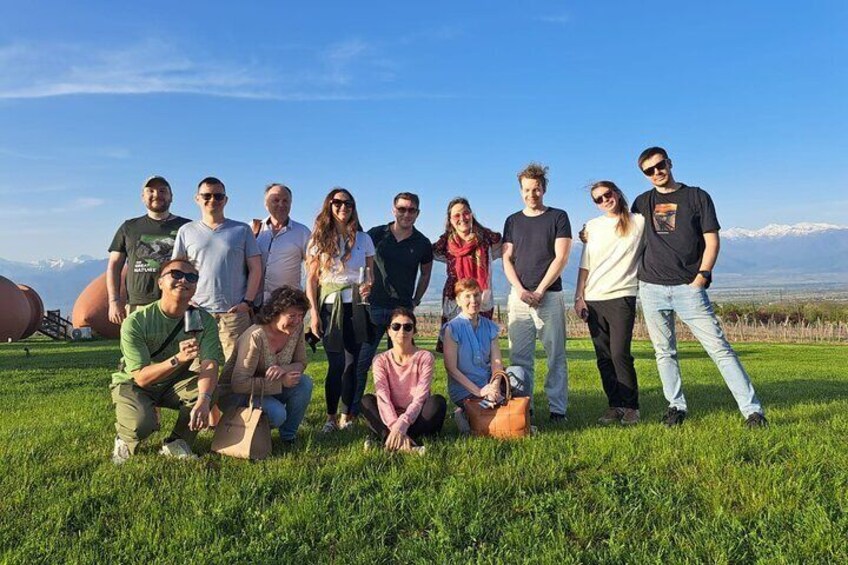 A group of people posing on a grassy field with mountains in the background. 3