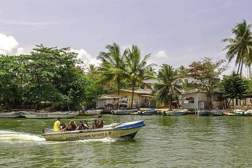 A boat named 'Bridgetown Spirit' on a river with palm trees and buildings in the background. 4