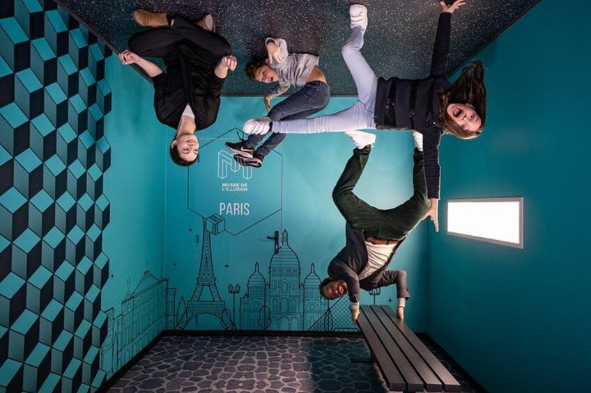 A room with a geometric pattern on the walls, a depiction of the Eiffel Tower, and a sign that says 'MUSEUM DE L'ILLUSION PARIS.' 4