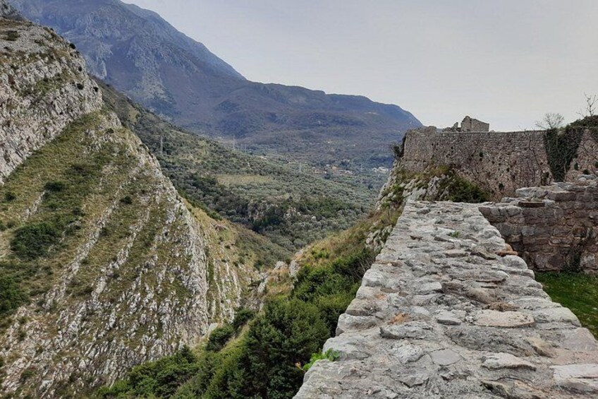 A stone pathway leading through a mountainous landscape with a historical stone structure on the right. 4