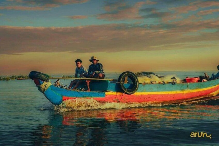 Ein buntes Boot mit zwei Personen, das auf dem Wasser treibt. 5
