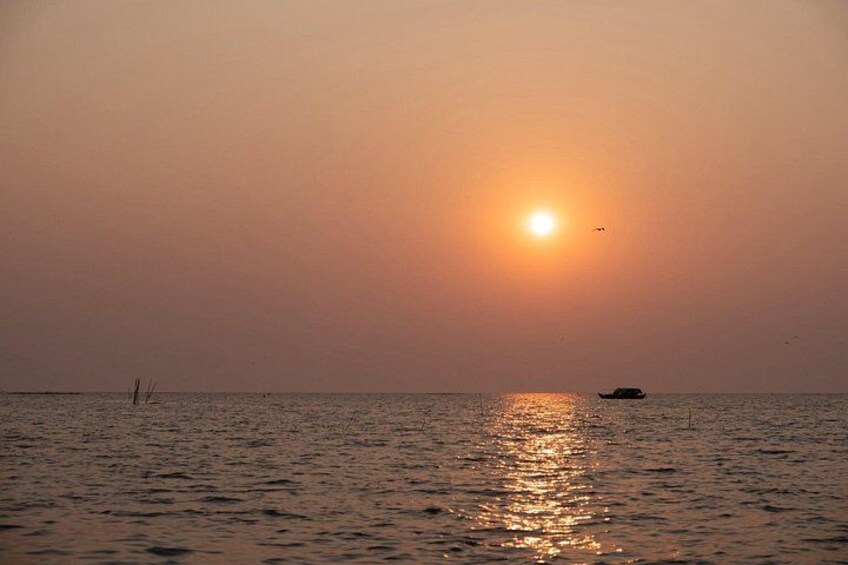 Ein Sonnenuntergang über einem ruhigen Meer mit einem Boot in der Ferne. 1