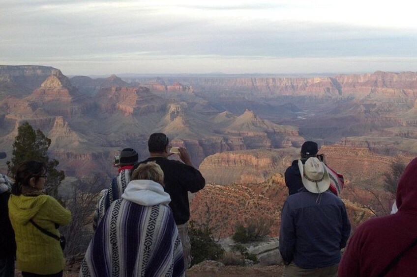 A group of people observing a vast canyon landscape. 3