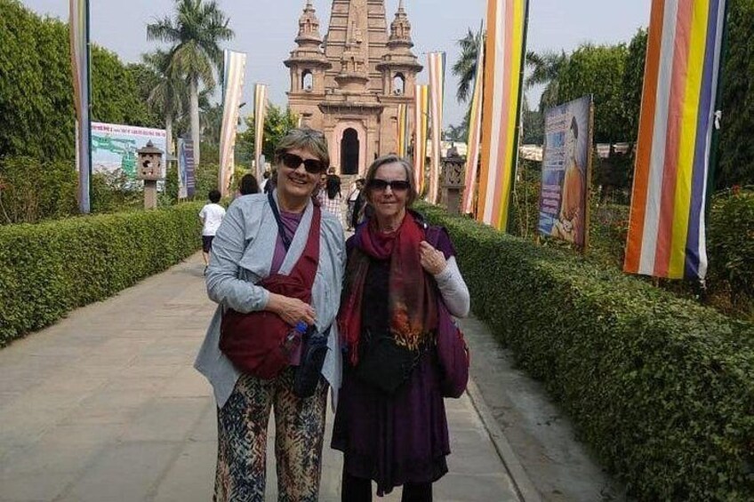 Two people standing in front of a temple with a pathway and greenery. 5