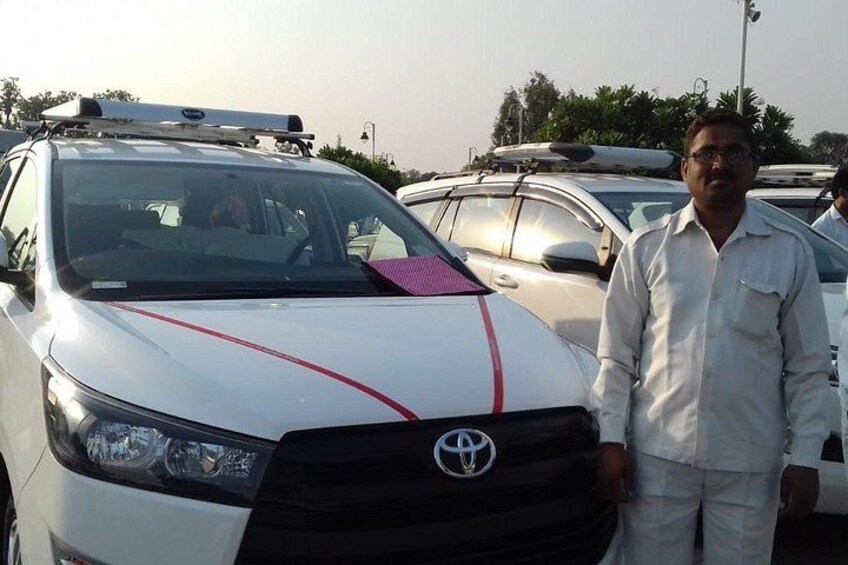A white car with a red stripe and a Toyota logo, parked in a lot with other vehicles. 2