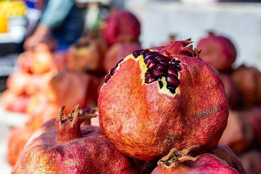 A pomegranate with a partially opened top, surrounded by other pomegranates. 3