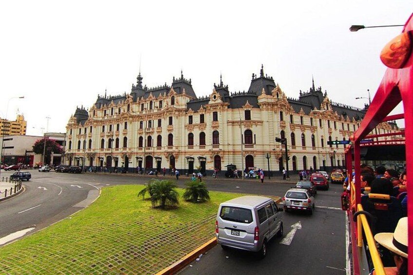 A historic building with ornate architecture, a road with vehicles, and a red bus. 2