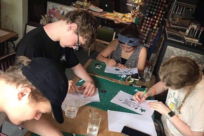 Four people engaged in a drawing activity at a table with art supplies. 2