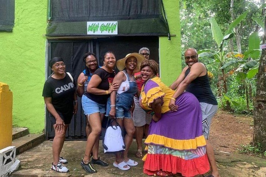 A group of people posing in front of a building with a green exterior and a sign that reads 'Hotel Grillo'. 4