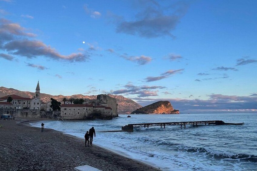 A coastal town with a historic building, a rocky shoreline, and a pier extending into the sea. 2