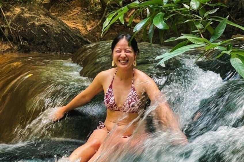 A person in a bikini sitting in a waterfall. 5