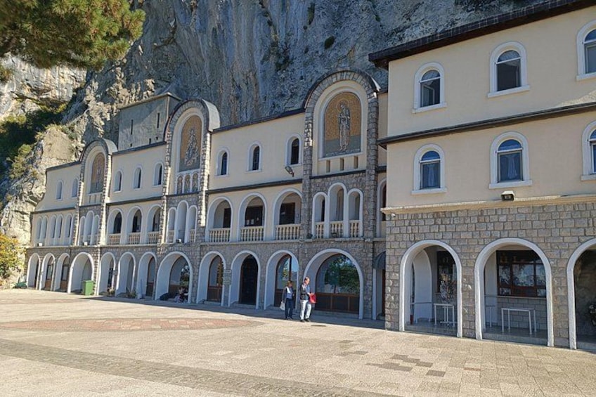 A historic building with arched windows and a stone facade, set against a mountainous backdrop. 4