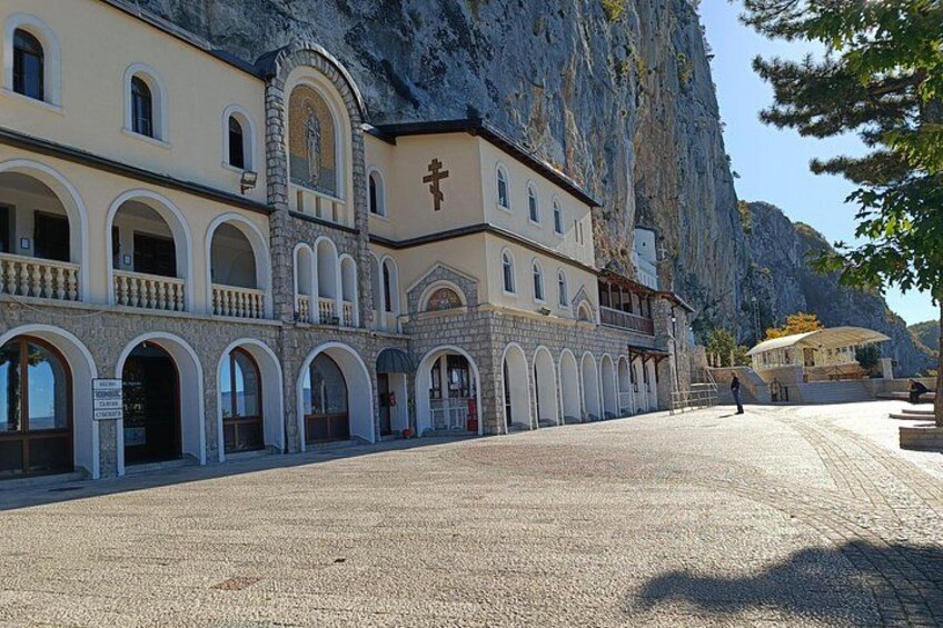 A building with arched windows and a stone facade, set against a cliff. 5