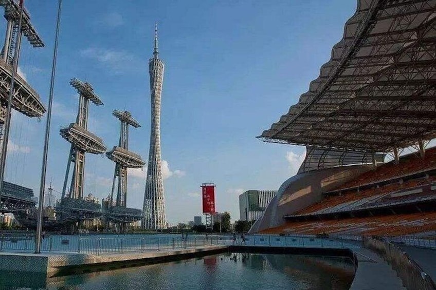 Un estadio moderno con una torre alta, zonas de asientos y una fuente de agua. 2