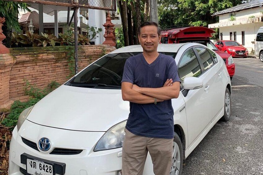 A man standing in front of a white car with a license plate. 4