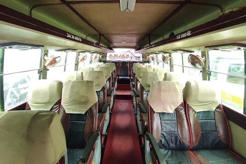 A bus interior with rows of seats, a red carpet, and overhead luggage racks. 3