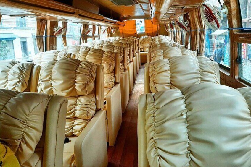 The interior of a train with plush, cream-colored seats and wooden paneling. 1