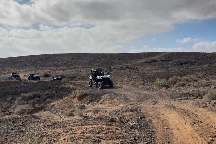 Off-road vehicles on a dirt path in a barren landscape. 3