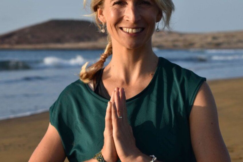 A person with clasped hands, standing on a beach with waves in the background. 2