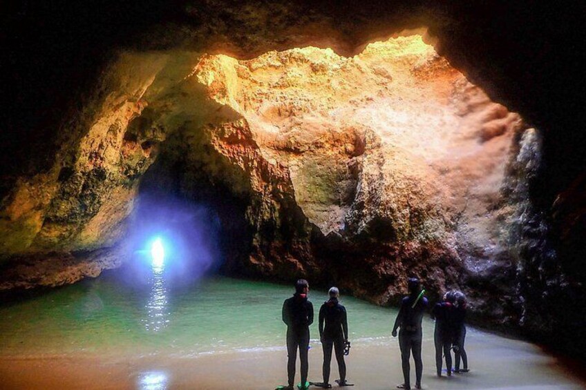 A cave with a pool of water and people standing at the entrance. 5