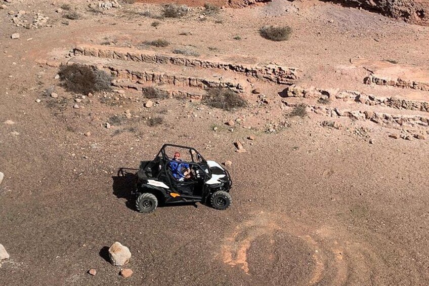 A vehicle on a rocky terrain with sparse vegetation. 5