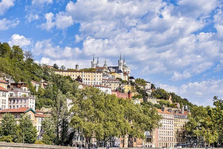 A hillside with historic buildings, a prominent church with a dome, and lush green trees. 3
