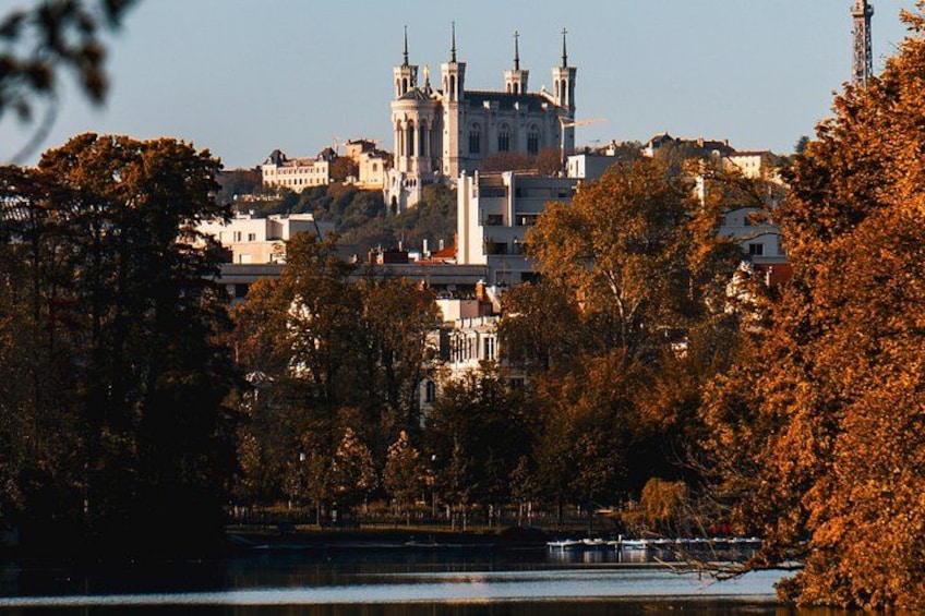 A historic cathedral with multiple spires, surrounded by autumn-colored trees and a body of water. 2