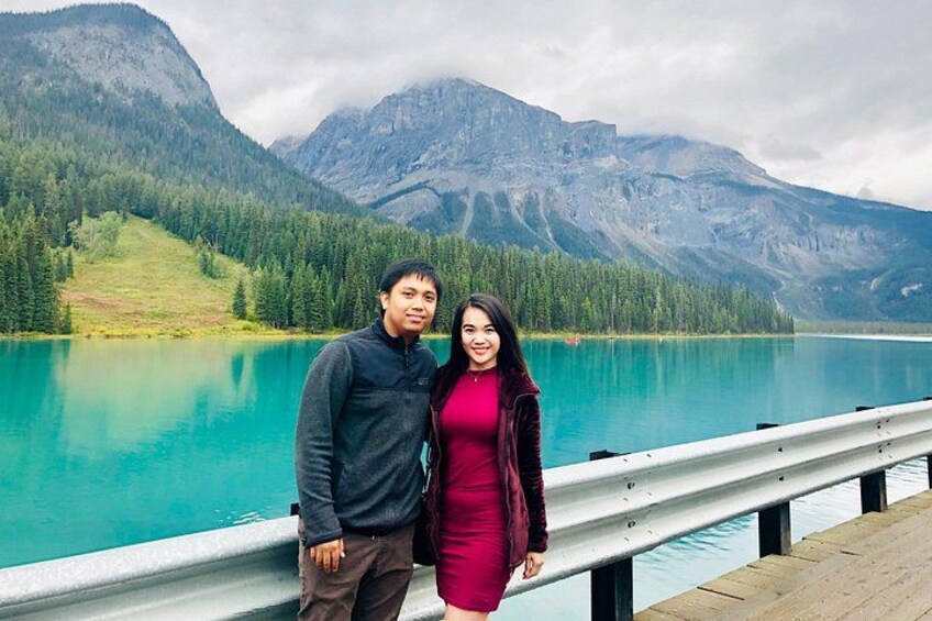 Un couple se tient sur une jetée en bois, au bord d’un lac turquoise, avec des montagnes en arrière-plan. 5
