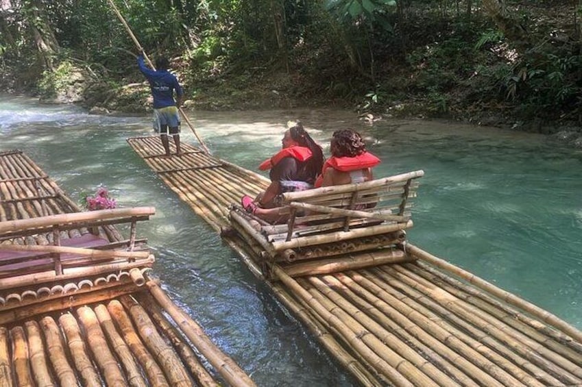 Menschen überqueren einen Fluss auf Bambusflößen, angeführt von einem Führer. 4