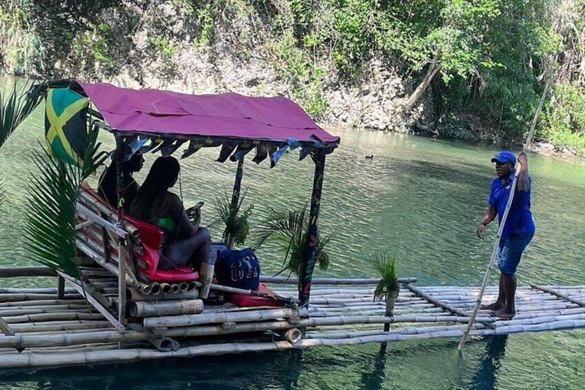 Una balsa de bambú con toldo, una persona de pie en el borde y un río tranquilo. 2