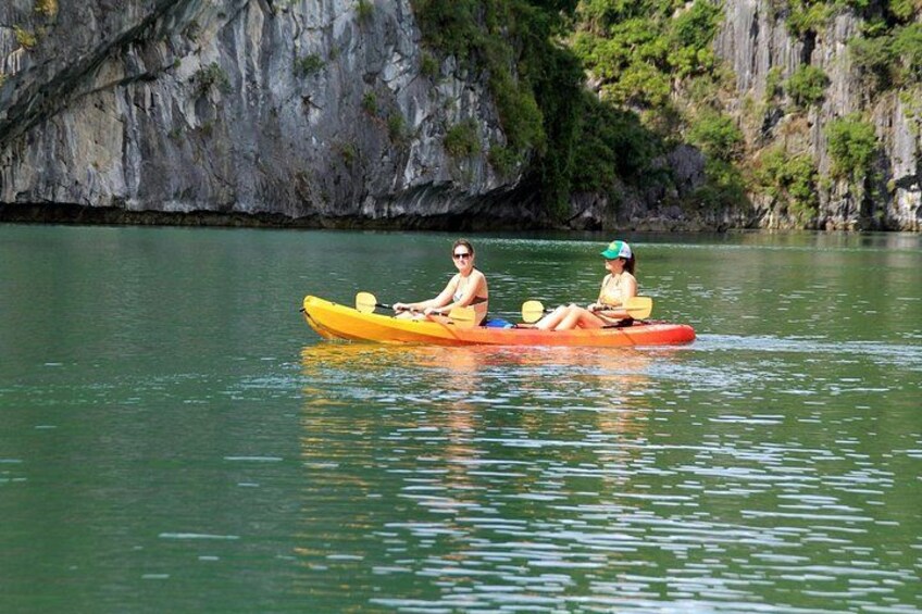 Two people kayaking on a calm river with rocky cliffs in the background. 5