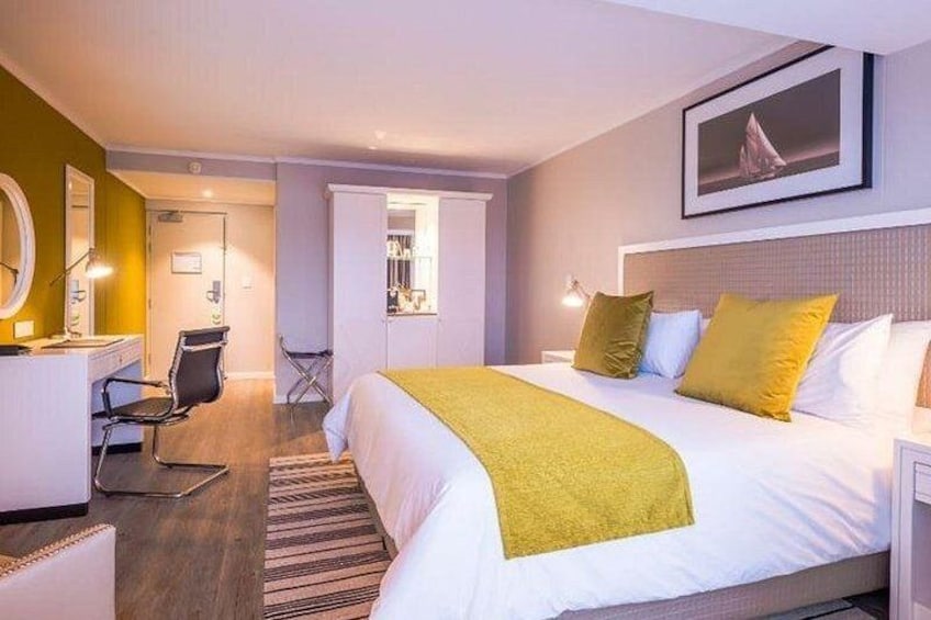 Een hotelkamer met een bed, nachtkastje, stoel en spiegel. 2