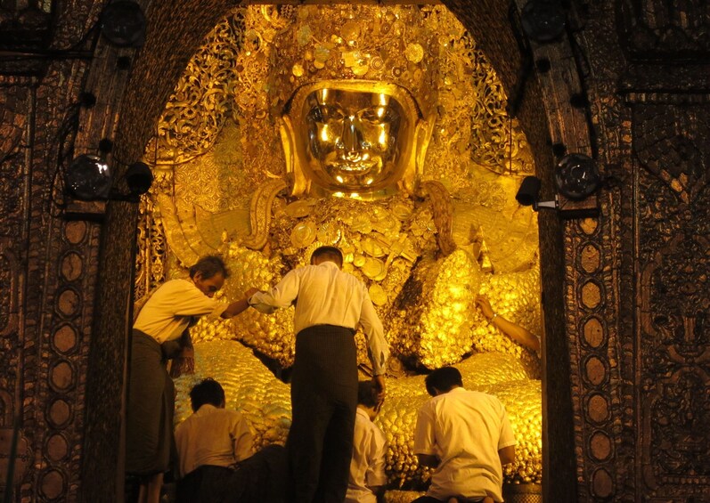 Un grupo de personas limpiando una estatua dorada de Buda en un templo. 3