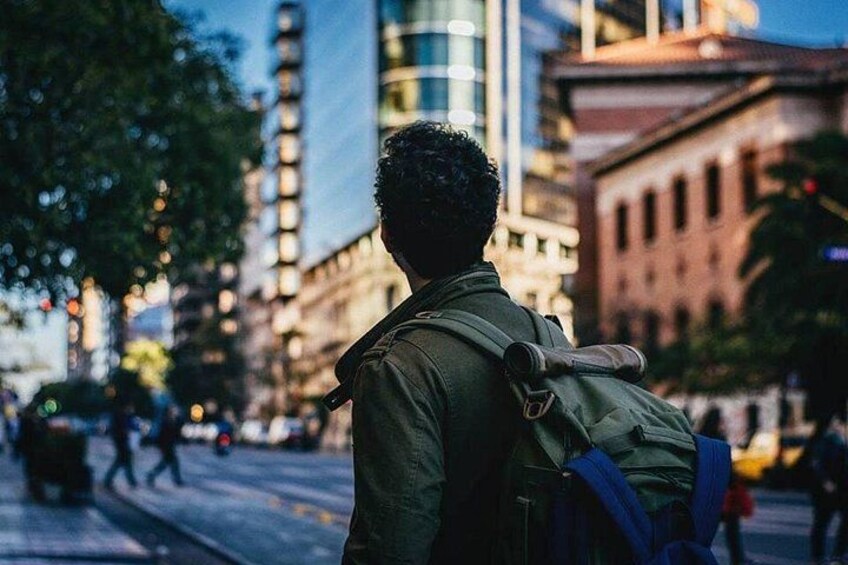 A person with a backpack walking on a city street. 2